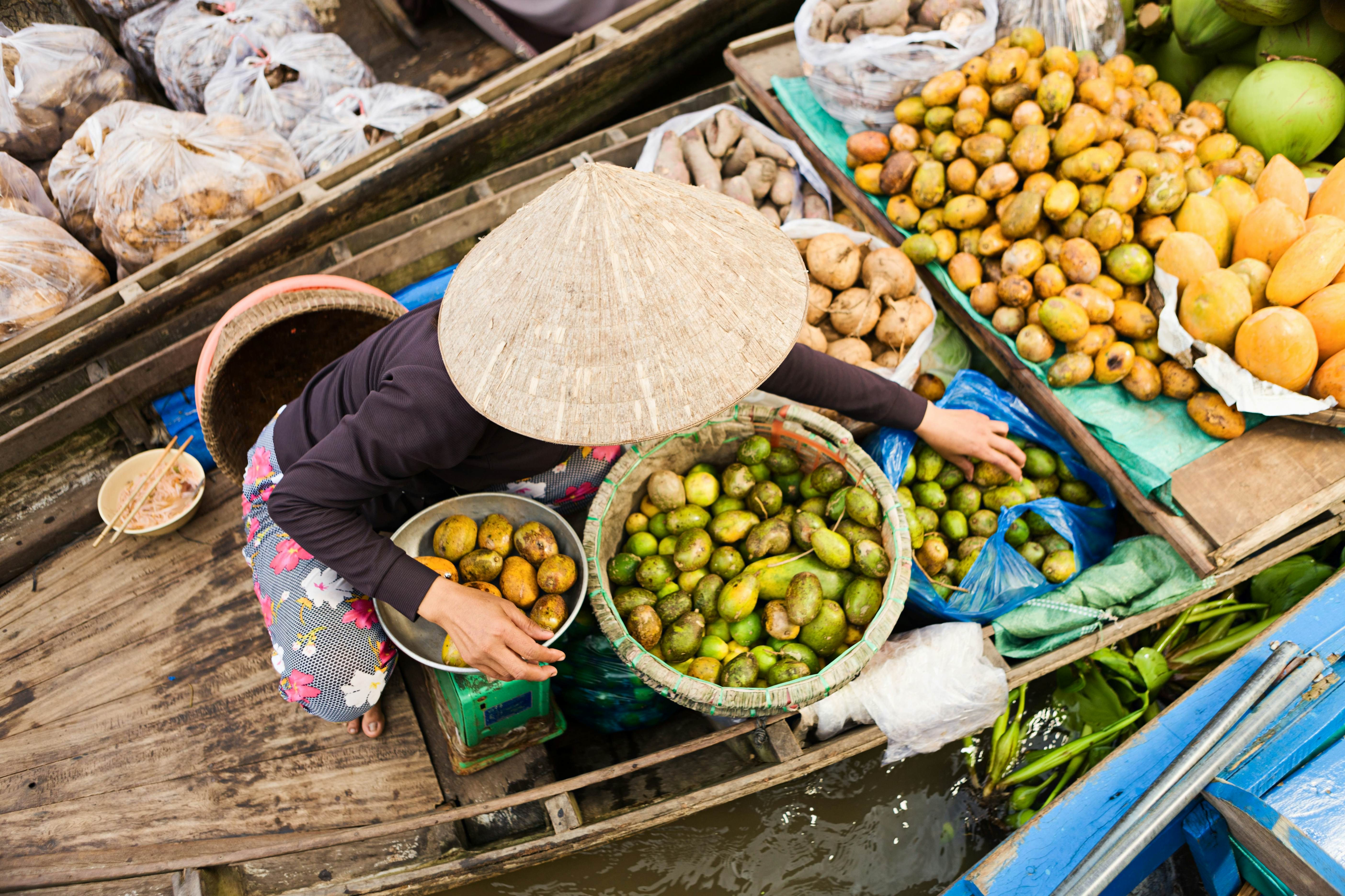 "Vietnamese fruits seller on floating market - woman selling fruit from her boat in the Mekong river delta, Vietnam."